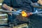 Old craftsman with scissors cutting and blowing the glass in fusing temperature to make a bottle with the old technique of blown