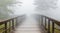 An old, creaky wooden bridge surrounded by mist