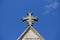 An old cross sits against a blue sky atop a church