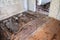 Old and crumbled wooden floor in old house, torn wallpapers. Construction debris
