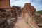 Old crumbling overgrown brick wall in front of stupa at historic park thailand