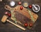 Old cutting board with spices and herbs for cooking meat with cherry tomatoes and a hammer meat place for text,frame