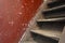 Old damaged brown wooden stairs and red wall leading to the attic, needs renovation