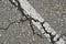 Old damaged cracked asphalt road section with old paint road marking. Texture damage. Deterioration of the road surface