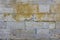 Old damaged gray wall of large stone bricks with yellow spots of paint. rough surface texture