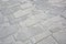 Old and damaged italian paving made with chiseled grey sandstone blocks in a pedestrian zone