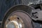 Old and damaged rear brake discs with caliper and brake pads in the car, on a car lift in a workshop.