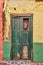 Old damaged wooden door of an abandoned weathered building. Vintage broken and aged green entrance to a house in a small