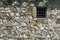 Old dark age stone wall and small prison cell window with bars