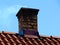 Old decaying chimney on light brown clay tile roof