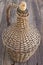 Old demijohn wicker wrapped glass bottle on wooden table