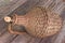 Old demijohn wicker wrapped glass bottle on wooden table