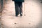 Old depressed woman walk alone down the street with walking stick or cane feeling lonely and lost view from back