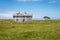 Old deserted wooden farmhouse on a green field. Lonely house in a picturesque landscape. Old abandoned farm house