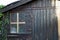 Old desolate barn with dirty vintage window, cute small house on back yard