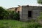 Old destroyed buildings among trees and green grasses. Abandoned buildings. Landscape