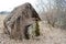 An old, dilapidated little wooden abandoned ruined rustling broken house of woods, logs and sticks overgrown with moss and plants