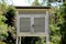 Old dilapidated white wooden box made for outdoor housing of weather instruments mounted on metal construction