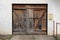 Old dilapidated wooden garage doors with mailbox mounted on right side wall