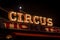 Old dimly lit circus sign with light bulbs in the dark over a ticket stand. Typical view of an entrance to a circus. Concept of