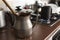 Old dirty cocoa cooking pot over kitchen furniture with gas stove on and others cooking pots at background.