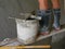 Old dirty grungy bucket and PVC plastic trowel on a wooden stand, being used for cement plastering by a construction worker