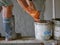 Old dirty grungy bucket on a wooden stand, being used for cement plastering by a construction worker