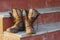 Old and dirty military boots on the steps of the porch. Close-up