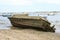 Old dirty and muddy boat on the sandy beach  with the new clean boats in the water