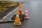 Old dirty traffic cones on the wet asphalt at the edge of the road