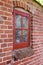 Old dirty window in a red brick house or home. Decaying casement with redwood frame on a historic building with clumpy