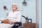 Old disabled woman reading book in wheelchair at home