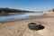 Old discarded car tire lying on the sandy bank of the river.