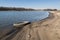 Old discarded car tire lying on the sandy bank of the river.