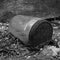 An old discarded dirty jar with a rusty lid lies on a messy floor against an old cracked wall