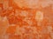 Old distressed patched orange stone wall painted in different shades of faded stained bright ochre paint