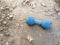 An old dog toy lies on the ground. An abandoned toy. Blue bone toy for dog. A toy for animals on the road.