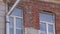 Old dusty house facade with brick wall and couple of windows in daylight.