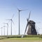 Old dutch windmill and modern wind turbines against blue sky in dutch province of groningen