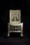Old egyptian wooden chair with carved decorations in a museum. Black background.