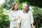 An old elderly Asian woman uses a walker and walking in the backyard with her daughter.  Concept of happy retirement With care