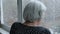 Old Elderly Caucasian Woman With Gray Hair Looks Out Of Window