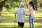 Old elderly using a walking stick to help her walk balanced with her asian granddaughter in outdoor nature,happy senior