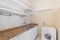 Old empty kitchen with shelves, tiled walls, marble countertop and washing machine.