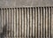 Old exterior concrete wall with fluted vertical stripe design with a rough cast texture with shadow