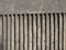 Old exterior dark concrete wall with fluted vertical stripe design with a rough cast texture with shadow