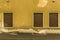 Old facade with 3 brown wooden shutters of a house with sidewalk