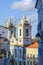 Old facades of colorful colonial-style houses, lanterns and windows and a tower of an old baroque church in Pelourinho
