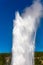 Old Faithful geyser shooting into the air in Yellowstone Park Wyoming with a blue sky