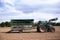 Old farm tractor with an empty open trailer in a plowed potato field, sunny autumn day, blue sky with clouds